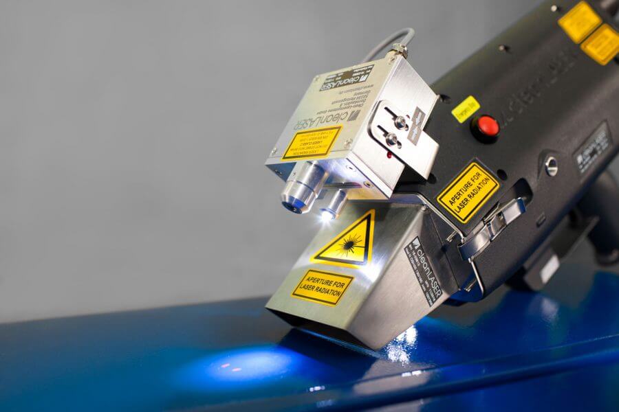 Close-up of cleanLASER handheld optics working on a blue coated surface