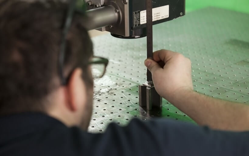 Technician positioning a sample beneath laser optics in an application testing lab